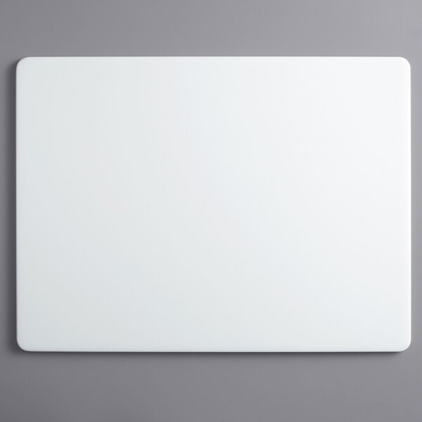 A white rectangular Vollrath cutting board on a gray surface.