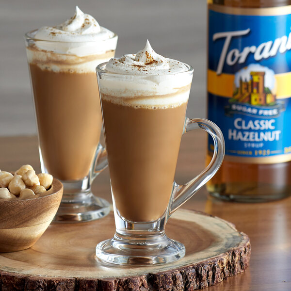 A glass of Torani Sugar-Free Classic Hazelnut Flavoring Syrup in coffee with whipped cream and nuts.