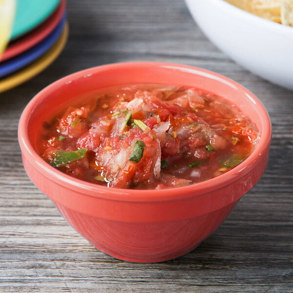 A bowl of salsa and a bowl of chips in GET Diamond Rio Orange melamine bowls on a table.