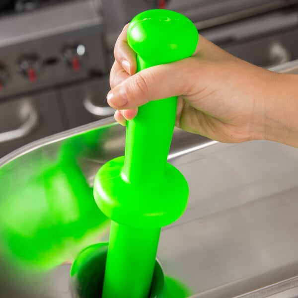 A hand holding a green plastic 12" Meat Tamper.