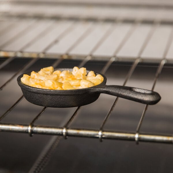 An American Metalcraft pre-seasoned mini cast iron skillet filled with macaroni and cheese on a table.