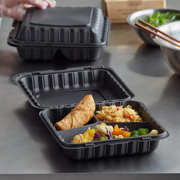 A table with Ecopax black plastic take-out containers filled with food.