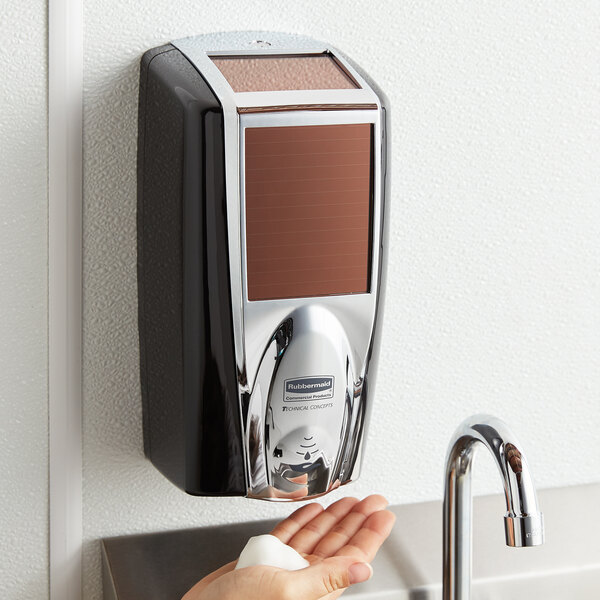 A person using a Rubbermaid Lumecel automatic soap dispenser to wash their hands.