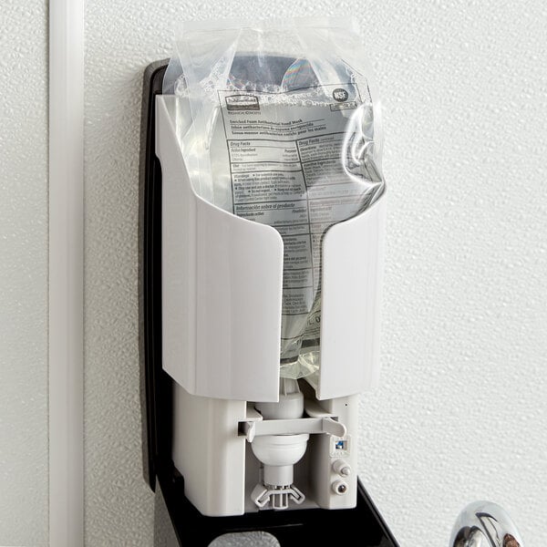A white Rubbermaid Autofoam wall dispenser with a bag of Rubbermaid Enriched Antibacterial Hand Soap inside.