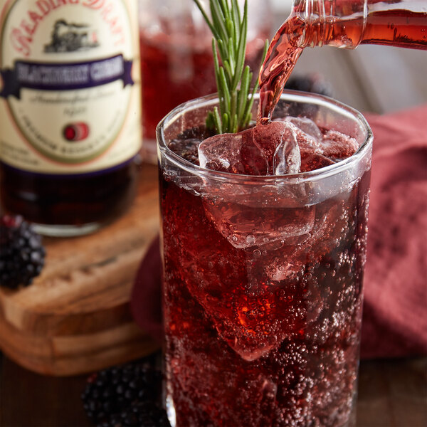 A glass of Reading Soda Works Blackberry Cream soda with ice on a table with a bottle of the soda.