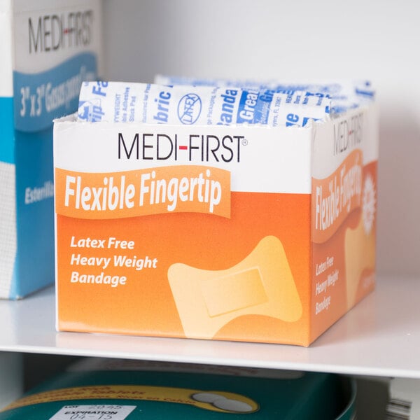 A box of Medique Medi-First woven fingertip bandages on a shelf.