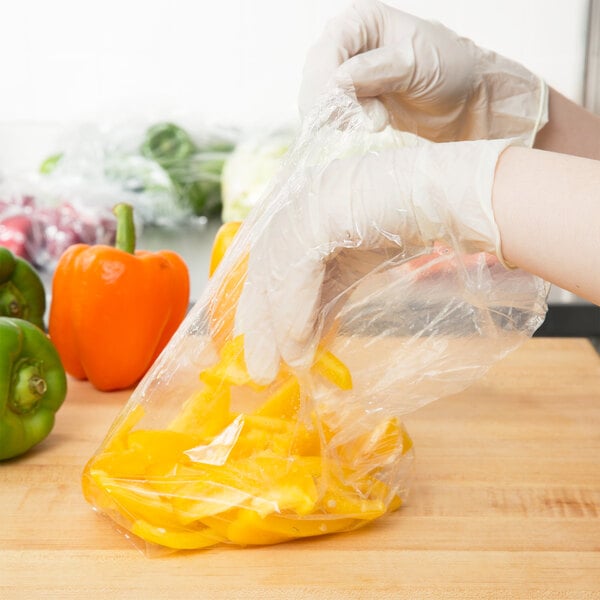 A person in gloves using a Inteplast Group plastic bag to hold yellow peppers.