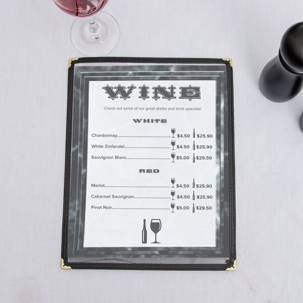 A black menu with a marble border on a table with a wine glass.