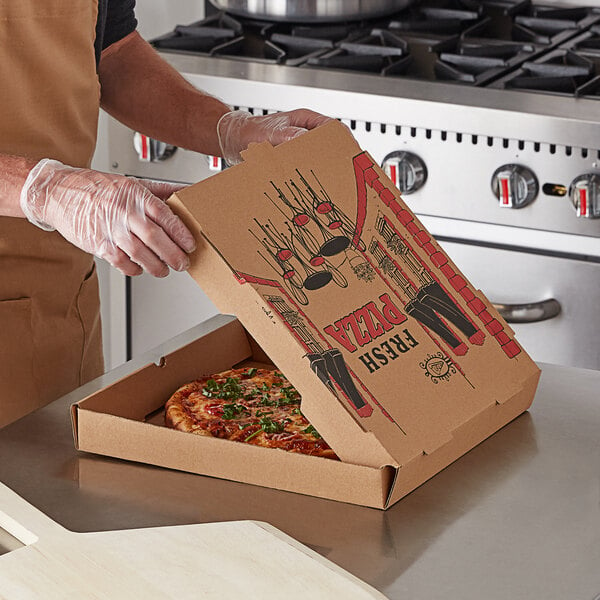 A person putting a pizza in a Choice Kraft corrugated pizza box.
