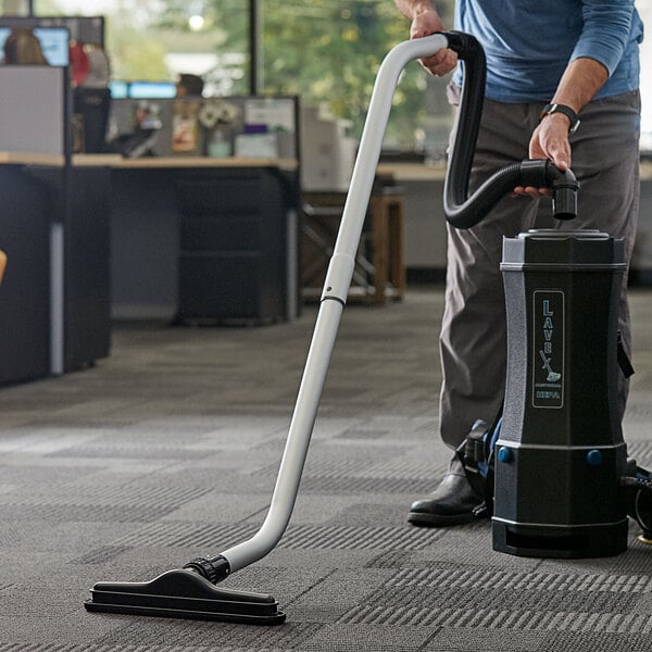 A person using a Lavex vacuum tool kit to vacuum the floor in a corporate office cafeteria.