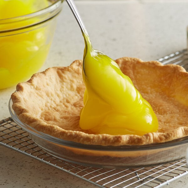 A spoon with Lucky Leaf lemon pie filling being poured into a pie.