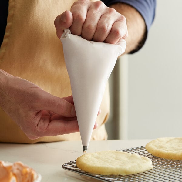 A person holding a white Ateco parchment pastry bag.
