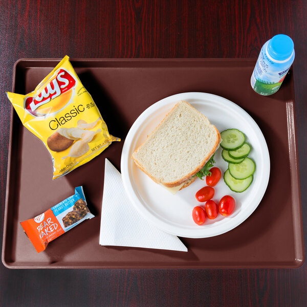 A tray with a plate of food, sandwich, and tomatoes, with a bottle of water.
