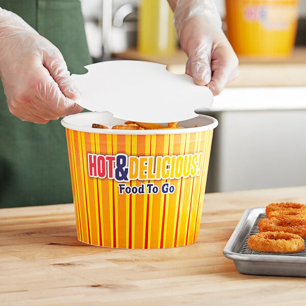 A person putting hot food into a yellow and red Choice hot food bucket.