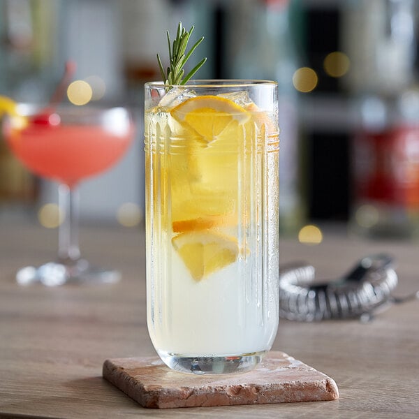 A Libbey highball glass filled with a lemon and rosemary cocktail on a table.