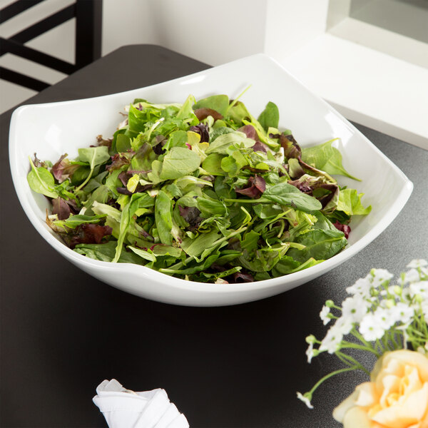 A white American Metalcraft square stoneware bowl filled with salad on a table.