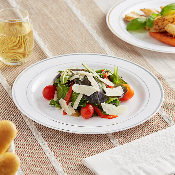 A Visions white plastic plate with a salad and a glass of wine.