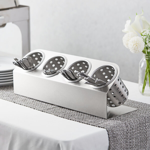 A Steril-Sil stainless steel flatware organizer with silver spoons and forks in perforated cylinders.