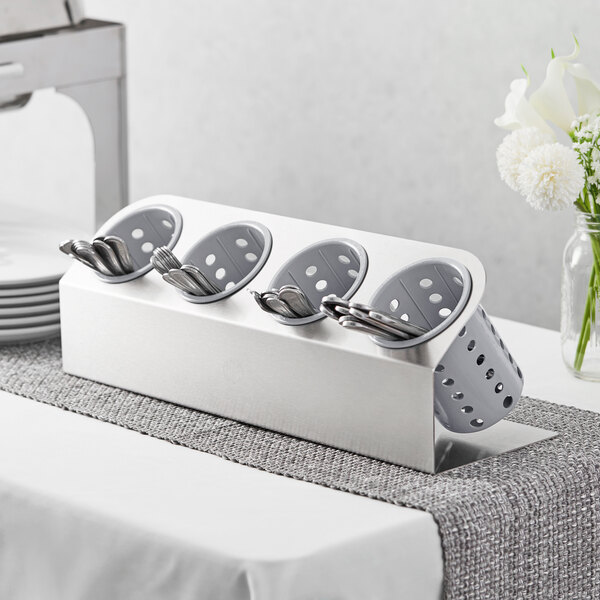 A Steril-Sil stainless steel flatware organizer with gray plastic cylinders holding silverware.