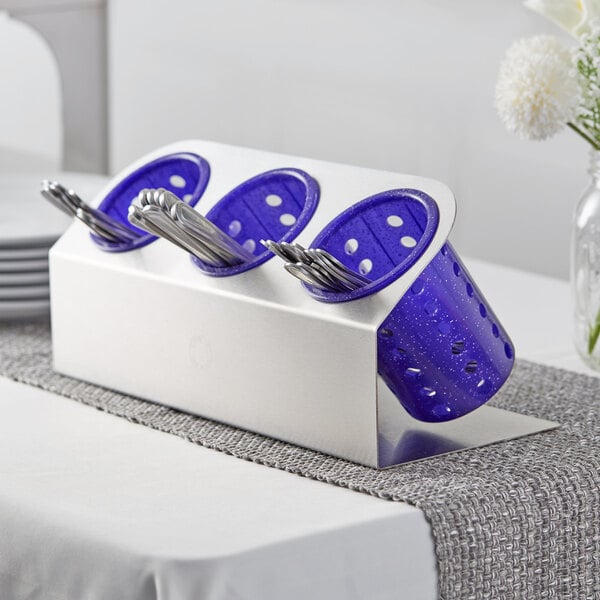 A Steril-Sil stainless steel flatware organizer with purple perforated plastic cylinders holding silverware.