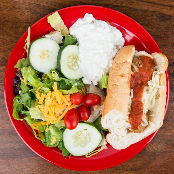 A Carlisle red melamine plate with a hot dog, salad, and rice on a table.