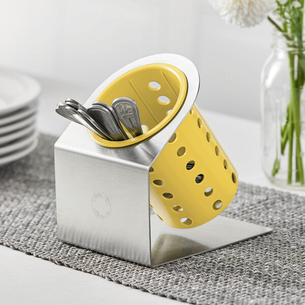 A Steril-Sil stainless steel flatware organizer with a yellow perforated plastic cylinder holding spoons.