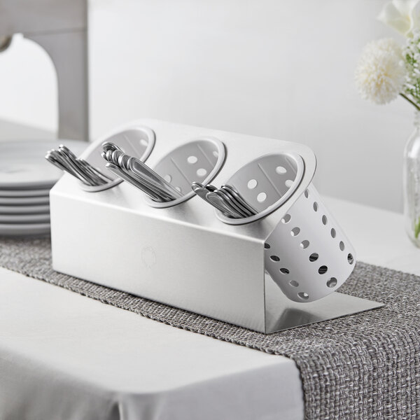 A Steril-Sil stainless steel flatware organizer with white plastic cylinders holding spoons and forks.
