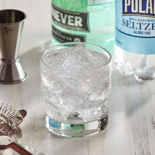 A glass of clear liquid with ice next to a bottle of Polar 1 Liter Natural Seltzer.