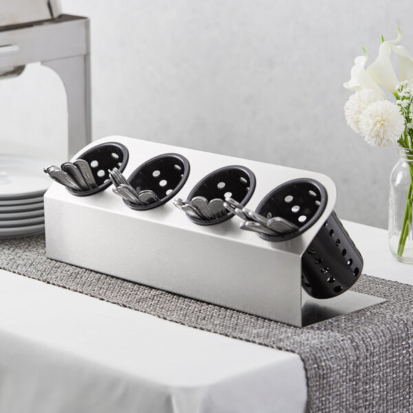 A Steril-Sil stainless steel flatware organizer with black perforated plastic cylinders holding silverware.
