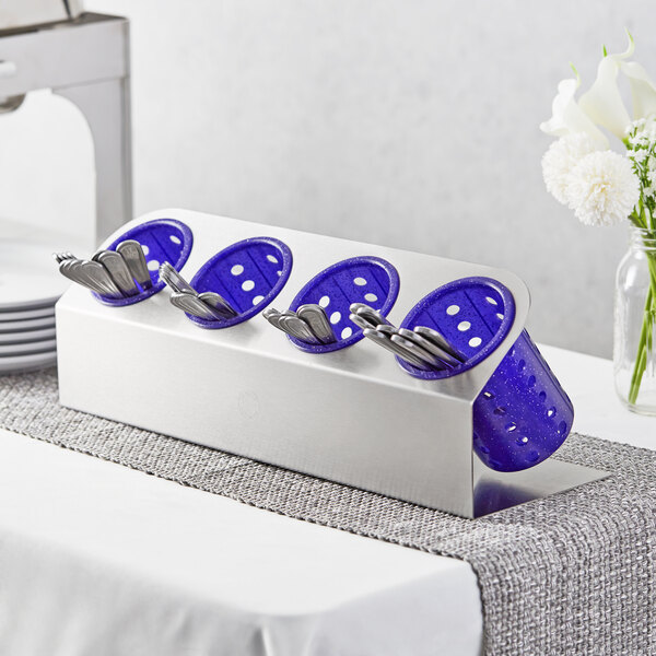 A Steril-Sil stainless steel flatware organizer with purple perforated plastic cylinders holding silverware on a table.
