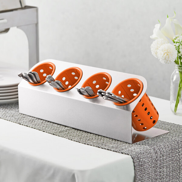 A Steril-Sil stainless steel flatware organizer with orange perforated plastic cylinders holding spoons and forks.