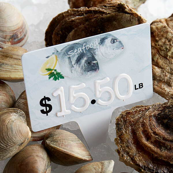 A Ketchum Manufacturing price tag with a seafood design on a pile of clams.