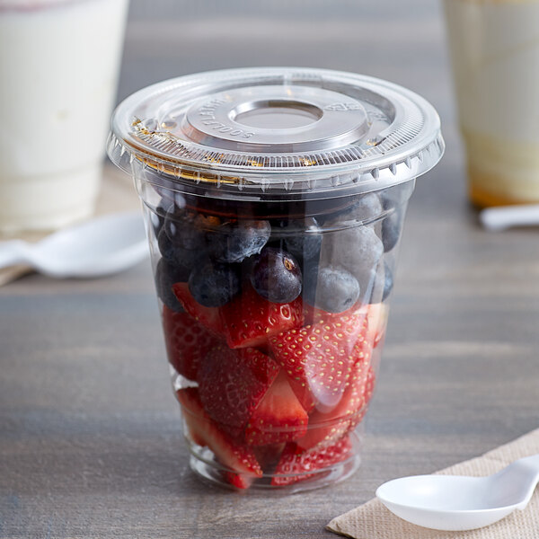 A clear plastic Choice cup with strawberries, blueberries, and yogurt.
