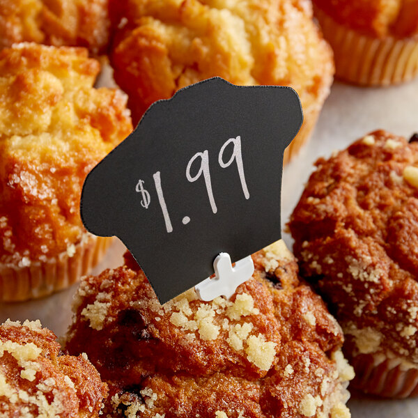 A Ketchum Manufacturing price tag on a muffin on a table in a bakery display.