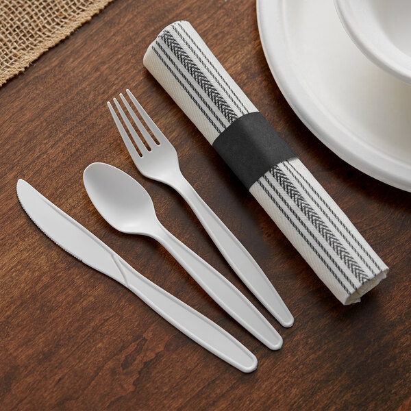 A white table with a place setting using Hoffmaster EarthWise cutlery with a black and white striped napkin and a spoon and knife.