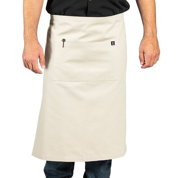 A man wearing a sand beige apron with natural webbing and a pocket.