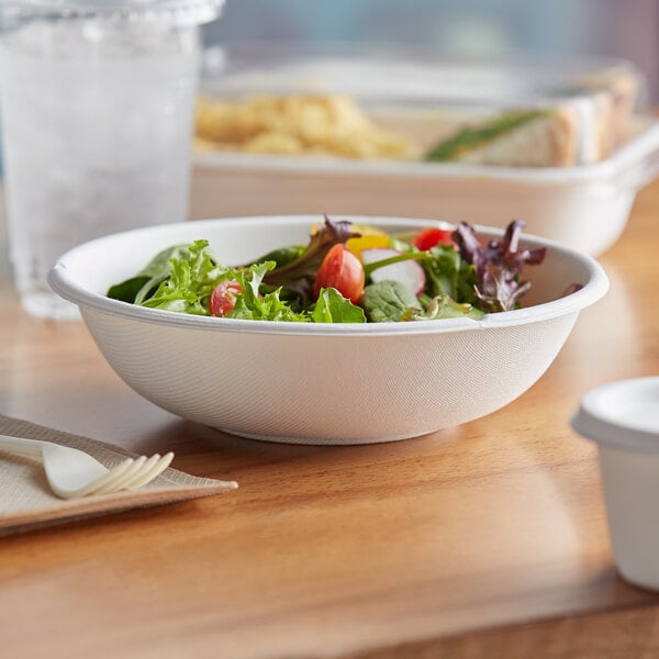 A bowl of salad with tomatoes and lettuce in a white Eco-Products WorldView compostable bowl.
