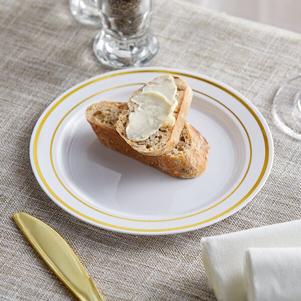 A Visions white plastic plate with a piece of bread and butter on it.