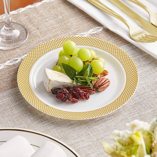 A Visions plastic plate with gold lattice design holding fruit and nuts with cheese and grapes.