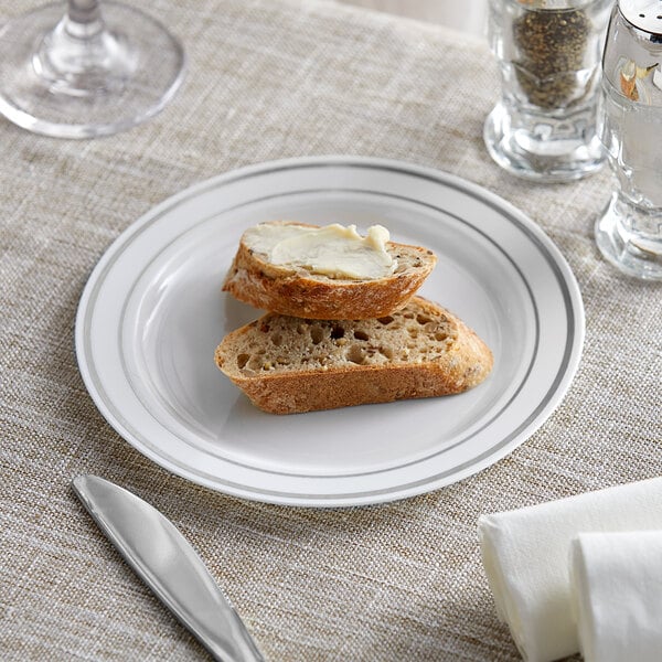 A Visions white plastic plate with a piece of bread and butter on it.