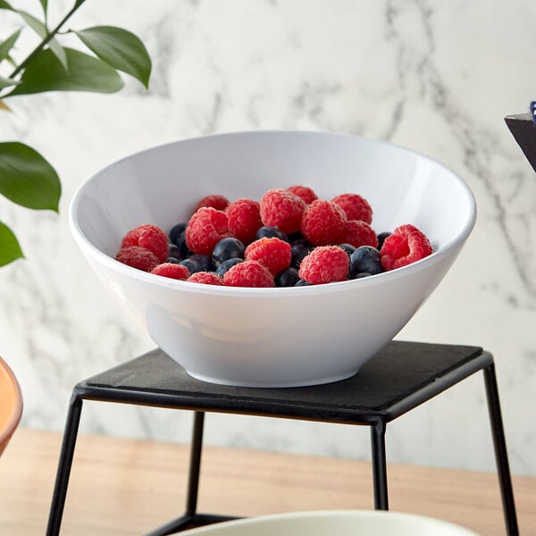 A white GET San Michele melamine bowl filled with raspberries and blueberries on a black stand.