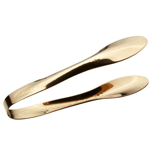 A pair of gold Bon Chef tongs with a hammered handle and spoon ends.