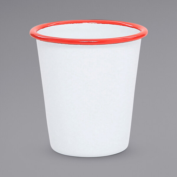 A white enamelware tumbler with a red rim.