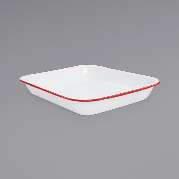 A white enamelware roasting pan with red trim.