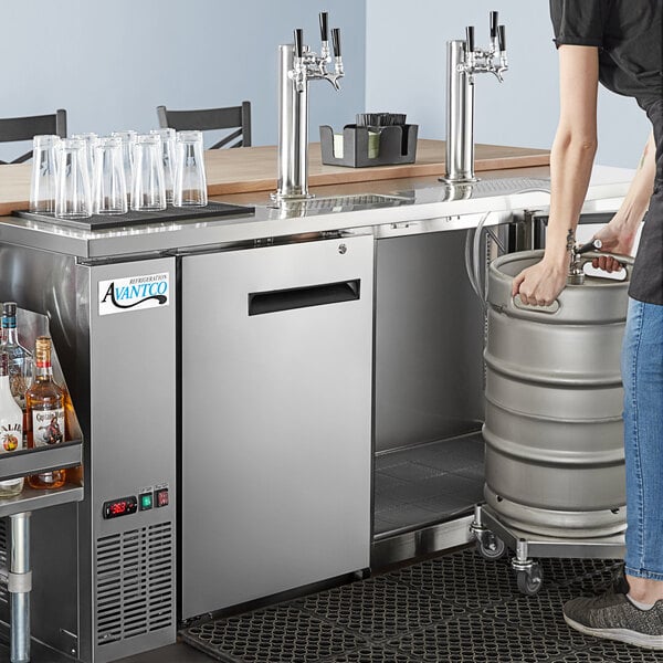A woman using a triple tap tower to dispense beer from a keg.