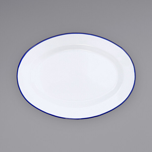 A white Crow Canyon Home enamelware plate with a blue rim.