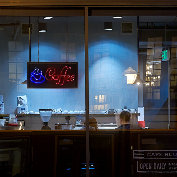 An LED coffee sign in a window.