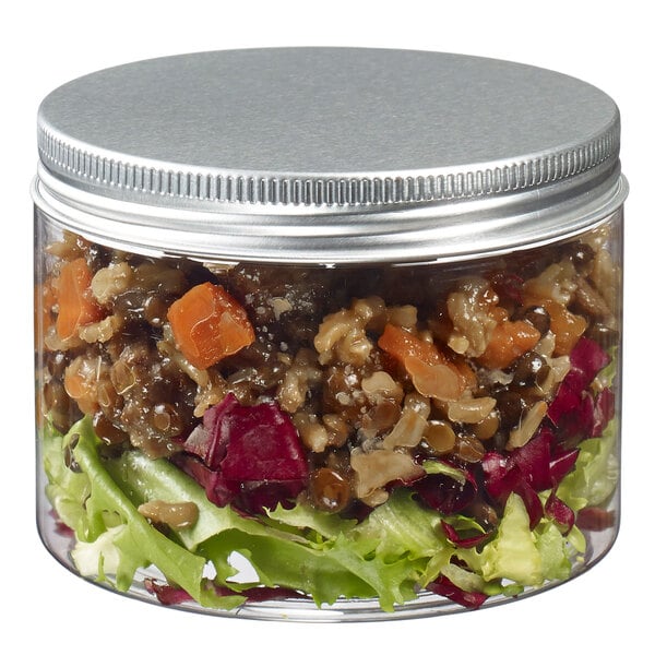 A Solia clear plastic jar with a silver lid filled with salad.