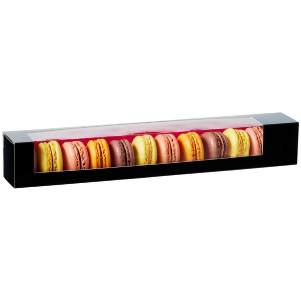 A black Solia Gourmandine box filled with colorful macarons.
