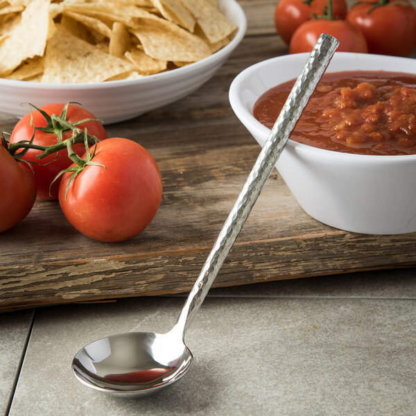 A Carlisle stainless steel ladle next to a bowl of red sauce and chips.